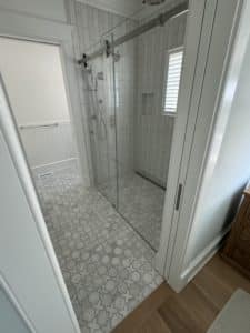 A large, open shower with white tiled floors and walls. 