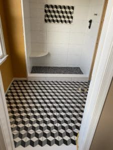 A unique shower with orange walls and black-and-white designed floors. 