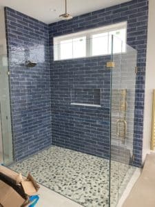 An open shower with blue-tiled walls and a textured floor. 