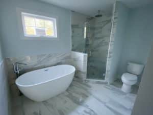 A bathroom with blue walls and marble tiling on the floor and in the shower.