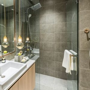 Modern bathroom with a glass-enclosed shower, large gray tiles, and a sleek vanity with a white basin and wood finish.